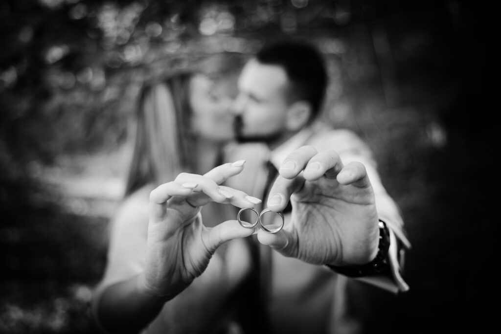 A couple shares a romantic moment, holding wedding rings with focus in Brașov.